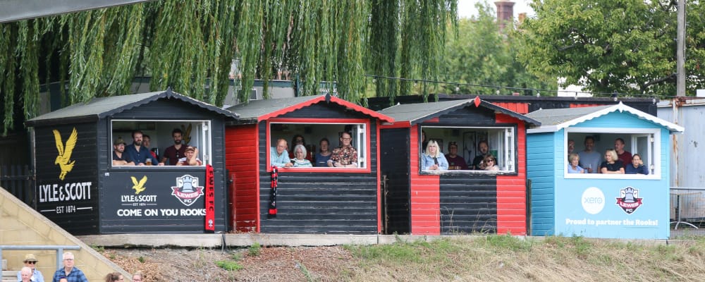 Lewes FC fans watch match from huts along the pitch sidelines